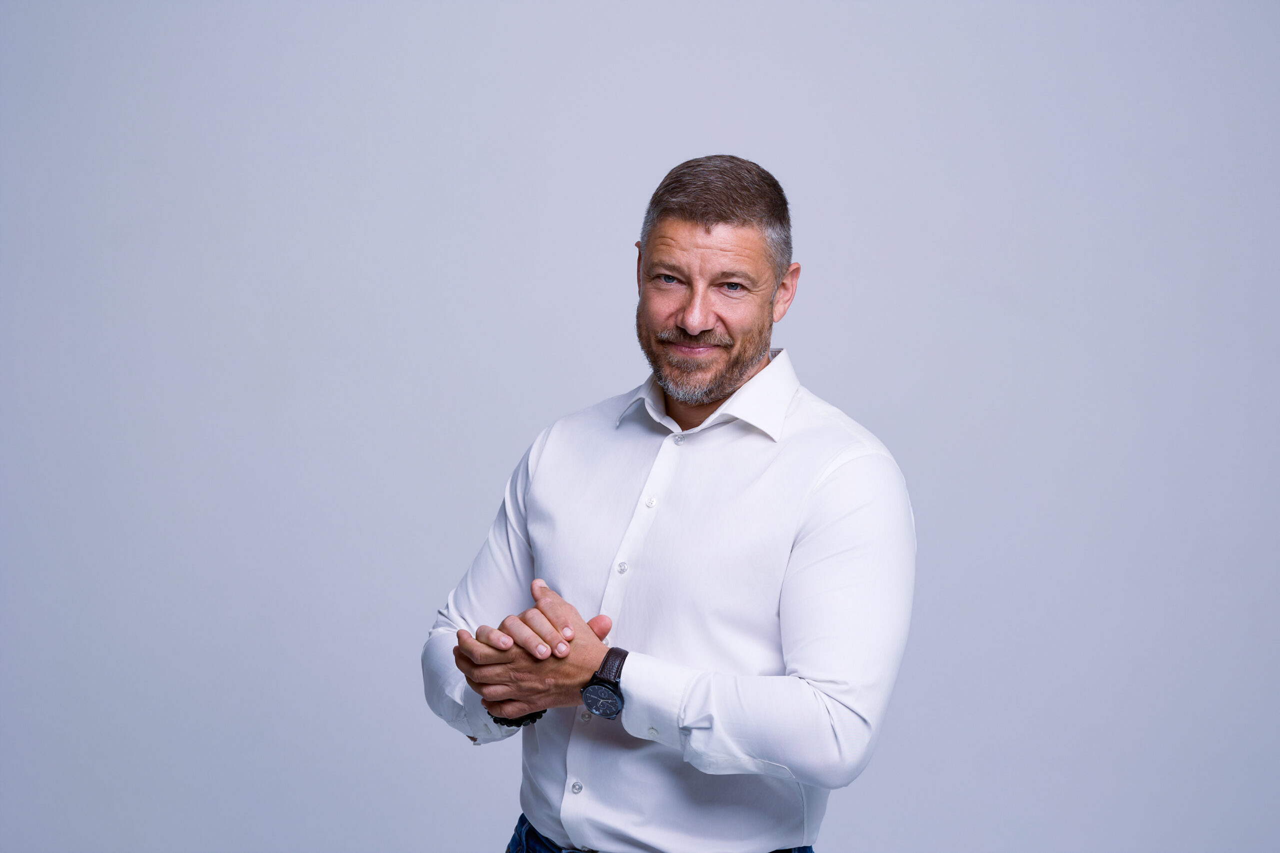 Mężczyzna w białej koszuli podczas profesjonalnej sesji biznesowej na jasnym tle w Poznaniu